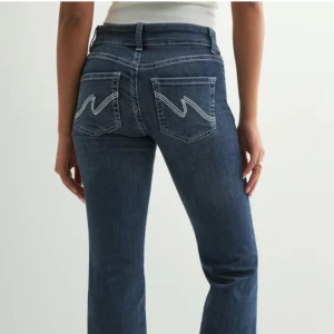 Nelly Jeans Bootcut - Snygga blå jeans med bootcut passform och coola broderade detaljer på bakfickorna. Jeansen har lågmidjad passform, klassisk femficksdesign och stängs med dubbla knappar och dragkedja. Byxorna har lite lätta slitningar längst ner, skriv för bilder💕💕