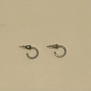  Små örhängen silver  - Säljer ett par minimalistiska silvriga hoops örhängen i rund form. De är små och stilrena, perfekta för dig som gillar enkel och clean stil. Passar till alla tillfällen och är lätta att matcha med andra smycken.