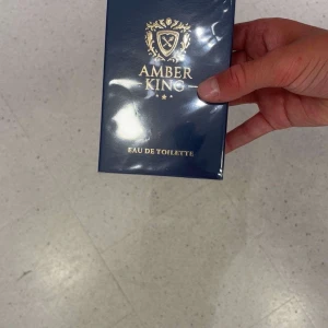 Amber King Eau de Toilette La Rive - Amber King Eau de Toilette från La Rive. Flaskan är rektangulär i genomskinligt glas med guldfärgat lock och svart text. Parfymen kommer i en elegant mörkblå kartong med gulddetaljer och klassisk logga. Perfekt för dig som gillar stilrena och lyxiga dofter.