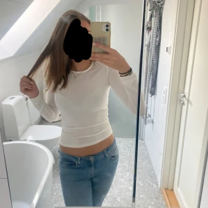 Vit långärmad tight tröja - Säljer en vit långärmad tröja med tight passform. Tröjan är enkel och stilren med rund halsringning och sitter snyggt figurnära. Perfekt att matcha med jeans eller kjol för en clean look.