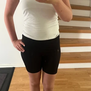 Svarta cykelshorts i stretch - Svarta cykelshorts med hög midja och tight passform. Gjorda i ett stretchigt och mjukt material som sitter skönt mot kroppen. Perfekta för träning eller när du vill ha en sportig look. Klassisk modell utan synliga detaljer eller mönster.