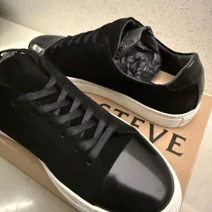 Svarta sneakers från Steve Madden - Stilrena svarta sneakers från sneaky steve med vit sula. Ovandel i mocka och tåparti i blankt skinn ger en snygg kontrast. Klassisk rund tå och snörning framtill. Perfekta för dig som gillar en clean och modern look.(oanvända)