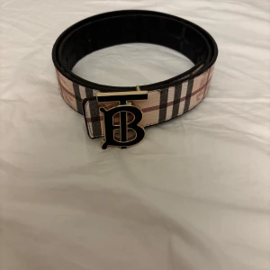Burberry bälte - Snyggt bälte från Burberry med klassiskt rutig design i beige.Helt ny.110 cm