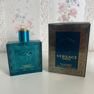 Versace Eros Eau de Parfum 100ml - Versace Eros Eau de Parfum i en lyxig turkosblå glasflaska med guldiga detaljer och Medusa-huvudet ingraverat. Flaskan rymmer 100 ml och har en stilren, fyrkantig form. Kommer med originalkartong i matchande färger och mönster.
