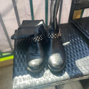 Boots med nitar på - Säljer ett par svarta boots med nitar från Mywear, storlek 39. Snygga och coola – perfekta till många olika outfits! Skorna är i fint och gott skick, men det finns några små skavanker som syns på bilderna. Bild 5 syns två nitar som saknas baktill på höger sko och en är på väg att lossna, samt lite slitningar vid tåspetsarna på båda skor Pris kan diskuteras.🙌🏻🙌🏻 Jag föredrar att skicka med PostNord