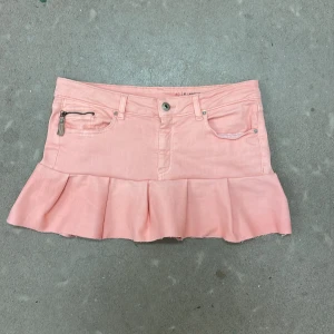Ljusrosa jeanskjol med volang - Supersöt ljusrosa kortkjol från edc med volangkant nertill. Kjolen har klassiska jeansfickor, dragkedja och knapp framtill samt en liten ficka med dragkedja. Storleken skulle jag säga är ungefär Storlek S, kanske lite mindre. Men om du vill veta mer om mått och längd kan du bara skriva. Priset kan diskuteras