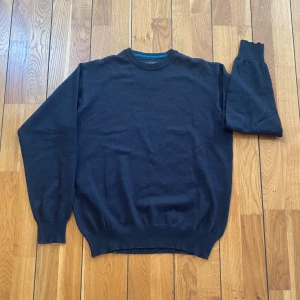 Svart stickad tröja från Folstop - En klassisk svart stickad tröja från Folstop med rund halsringning och ribbade muddar vid ärmslut och nederkant. Perfekt för lager-på-lager och enkel att matcha med jeans eller chinos. Materialet är mjukt och ger en skön känsla hela dagen.