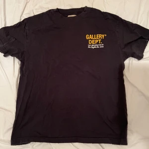 Gallery dept t shirt  - Svart t-shirt från Gallery Dept. med coolt färgglatt bilmotiv på ryggen och gul logga framtill. Klassisk passform och rund hals. Perfekt för dig som gillar streetwear och unika prints. Materialet känns mjukt och skönt mot huden.