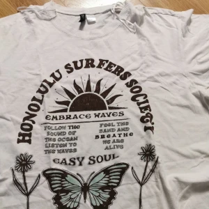 Vit t-shirt med tryck från H&M Divided - Söt Vit t-shirt från H&M Divided som kommer inte till användning långre, Skön passform och rund halsringning. Perfekt för dig som gillar chill och surf vibes. Hör av er om ni vill ha fler bilder för dessa kanske va inte då tydliga💕💕