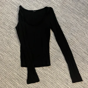 Svart långärmad topp med rund hals - En svart, tight långärmad topp med rundad halsringning. Enkel och stilren design som passar till det mesta. Tunn och mjuk i materialet, perfekt att styla med jeans eller kjol.