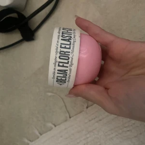 Sol de Janeiro Beija Flor Elasti-Cream - Beija Flor Elasti-Cream från Sol de Janeiro i en söt, rund rosa burk på 75 ml. Denna kroppskräm är känd för sin återfuktande och elasticitetsboostande formula med en fräsch doft. Perfekt för dig som vill ha mjuk och smidig hud.
