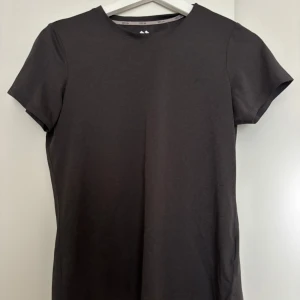 Mörkgrå tränings t-shirt från 157, XS - En stilren mörkgrå t-shirt från 157 i storlek XS. Modellen är klassisk med rund halsringning, korta ärmar och en liten slits i sidan. Perfekt basic-plagg i mjuk bomull som funkar till allt. Tränings t shirt. Knappt använd.