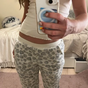 Leopardmönstrade mjukisbyxor i xxs - Supergosiga mjukisbyxor från KappAhl i vitt med grått leopardmönster. Byxorna har resår i midjan och muffar vid bensluten som går att vika upp, och är gjorda i ett fluffigt material.