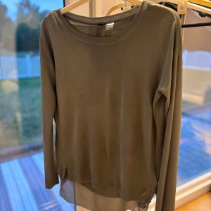 Olivgrön stickad tröja med ryggdetalj - Olivgrön stickad tröja från Gina Tricot med lång ärm och rund hals. Tröjan har en snygg öppen ryggdetalj och slitsar i sidorna. 