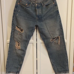 Blå relaxed jeans från Topman W34/L30 - Säljer ett par blå jeans från Topman i relaxed fit med slitna och trasiga detaljer på benen. Jeansen har klassisk femficksdesign, normal midja och raka ben. 