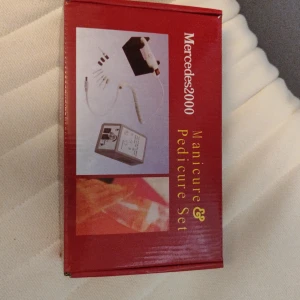 Mercedes2000 Manikyr & Pedikyr Set - Elektriskt manikyr- och pedikyrset med flera sliphuvuden, svart handstycke med röd knapp och grå kontrollenhet. Perfekt för att fixa naglarna hemma. Kommer i röd förpackning och passar både fingrar och tår.