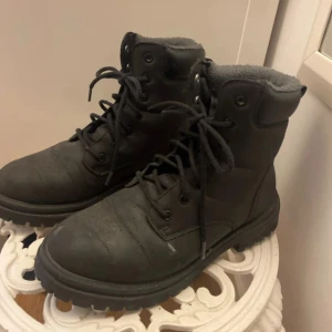 Svarta boots från Race Marine, stl 37 - Svarta boots från Race Marine med grov sula och snörning. Skorna har mjukt foder på insidan och är perfekta för kyligare dagar. Tillverkade i syntetmaterial med matt finish och rund tå. Snygga och praktiska för höst och vinter.