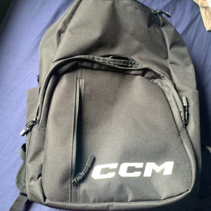 Svart ryggsäck från CCM - Säljer en svart ryggsäck från CCM med flera dragkedjeförsedda fack och justerbara axelremmar. Väskan har en stilren design med CCM-logga i vitt framtill och praktiska sidofickor. Perfekt för skola, träning eller vardagsäventyr.
