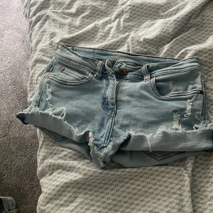 Ljusblå slitna jeansshorts - Snygga ljusblå jeansshorts med slitna detaljer och fransig kant. Klassisk femficksmodell med låg midja och knappstängning. Perfekta för varma dagar när du vill ha en chill och trendig look💘🥰