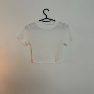 Vit croppad t-shirt - En stilren vit croppad t-shirt med rund hals och korta ärmar. 