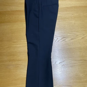 Svarta kostymbyxor från Zara - Klassiska svarta kostymbyxor från Zara med raka ben och diskreta fickor. Byxorna har bälteshällor och är sydda i ett slätt tyg som ger en stilren look. Perfekta för dig som gillar en clean och tidlös stil. Använd bara en gång. 