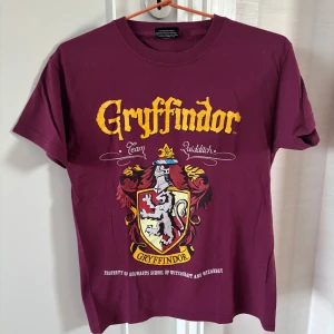 Vinröd Gryffindor t-shirt - Cool vinröd t-shirt med Gryffindor-tryck och  från Harry Potter. Finns inte storleksetikett men passar mig som bär storlek S. Otroligt fin och passar alla potterheads - inte bara gryffindors❤️!