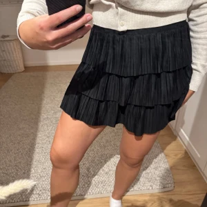 Svart volangkjol - Supersnygg svart kortkjol med flera lager volanger. Går att klä ner med en stickad tröja eller klä upp med en snygg topp🖤