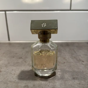 Hugo Boss The Scent for her parfym - Elegant parfymflaska från Hugo Boss The Scent for her med guldigt lock och detaljer. Perfekt för dig som gillar en lyxig blommig doft🌸