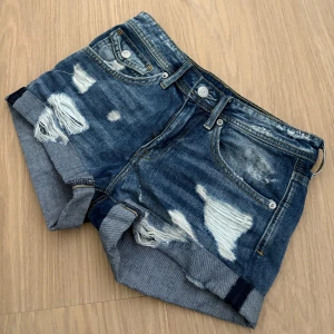 Blå jeansshorts med slitningar från Denim - Snygga blå jeansshorts med coola slitningar och uppvikta benslut. Storlek 32 men passar även 34 (som hon på bilden). Hör av er vid frågor 💓