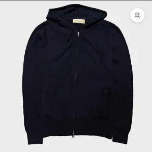 Mörkblå hoodie med dragkedja - Snygg mörkblå hoodie med huva och snörning, hel dragkedja framtill och två fickor. Perfekt för chill dagar eller när du vill ha en enkel och stilren look. Materialet känns mjukt och skönt mot huden.