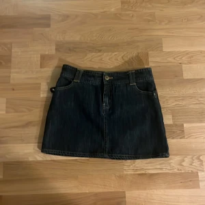 Mörk jeanskjol från H&M, storlek 36 - Säljer en snygg mörkblå jeanskjol från H&M i storlek 36. Kjolen är kort, har klassiska fickor både fram och bak samt bälteshällor. Perfekt för dig som gillar en enkel och stilren look med denim.