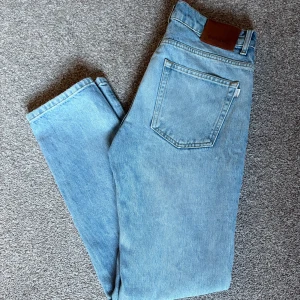 Ljusblå jeans från Woodbird - Snygga ljusblå jeans Storlek 29/32från Woodbird med klassisk femficksdesign och raka ben. Jeansen har en normal passform och är tillverkade i mjukt denimtyg Perfekta till sneakers och hoodie.