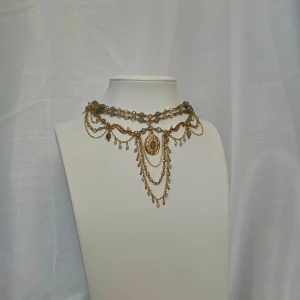 Handgjort halsband  - Ett halsband med både stora och små pärlor i labradorit samt små vita pärlor. Halsbandet har massor av guldiga kedjor och detaljer. Halsbandet har även en förlängningskedja<3