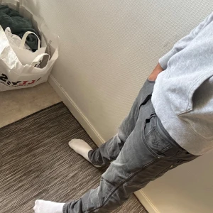 Replay grå jeans slim fit - Säljer ett par grå jeans från Replay med snyggt tvättad look och klassiska fem fickor. Jeansen har smal passform, normal midja och diskreta detaljer på bakfickorna. Perfekta för dig som gillar stilrena och bekväma jeans med lite edge.