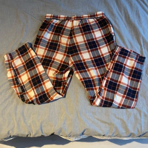 Rutig byxa från Jack & Jones S - Mysiga byxor från Jack & Jones i storlek S med rött, blått och vitt rutmönster. Byxorna är tillverkade i mjuk bomull, perfekta för chill dagar hemma. Klassisk loose fit och skön känsla.