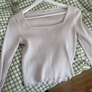 Ljusbeige ribbad topp från Sinsay - Superfin ljusbeige ribbad topp från Sinsay i storlek S. Den har långärmad design, fyrkantig halsringning och är gjord i mjukt stickat material. Perfekt att styla med jeans eller kjol för en chill och snygg look.