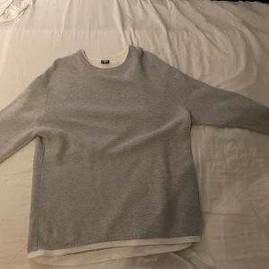 Ljusgrå stickad tröja från FSBN XL - Snygg ljusgrå stickad tröja från FSBN i slim fit-modell. Tröjan har rund halsringning och långa ärmar, perfekt för lager-på-lager. Materialet är mjukt och passar dig som gillar en clean och enkel stil.