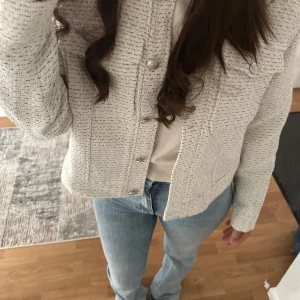 Beige overshirt med knappar - Snygg beige overshirt med diskret vävt mönster och silvriga knappar framtill. Jackan har två bröstfickor och en rak, croppad passform som ger en trendig look. Perfekt att slänga över en t-shirt eller stickad tröja. Den är i Stolek L men är liten i storleken, jag har storlek S/M och sen passar mig perfekt!