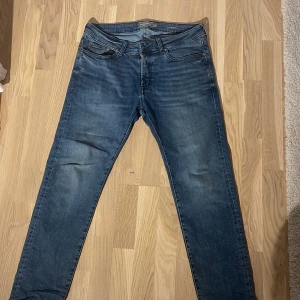 Blå jeans från Dressmann, straight fit - Snygga blå jeans från Dressmann i klassisk straight fit. Jeansen har fem fickor, normal passform och är tillverkade i slitstarkt denim. Färgen är mörkblå med lätt tvättade detaljer för en cool look. Perfekt för dig som gillar enkel och stilren design.