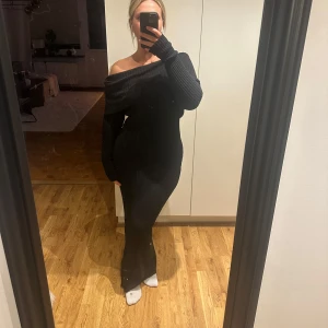 Svart stickad långklänning offshoulder - Stickad långklänning med offshoulder. Klänningen har en öppen ryggdetalj och sitter tight över kroppen. Storlek s men passar mellan s-l