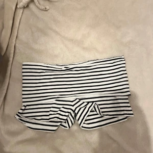 Randiga shorts från Gina Tricot - Säljer ett par svartvita randiga shorts från Gina Tricot. De är stretchiga och har en låg med bred linning. Perfekta för varma dagar och har en mjuk känsla mot huden. Passar dig som gillar en enkel men snygg stil.