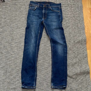 Blå jeans från Nudie Jeans, 29/30 - Säljer ett par blå jeans från Nudie Jeans i storlek 29/30. Jeansen har snygga slitningar. De har en rak/ mer åt slim hållet som passform
