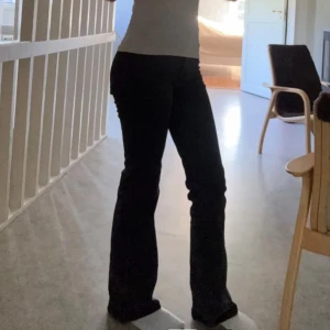Svarta bootcut jeans - Säljer ett par svarta jeans med bootcut-modell. Jeansen har klassisk femficksdesign och är tillverkade i ett bomullsmaterial som sitter snyggt över höfterna och låren. Perfekta för dig som gillar en tidlös och trendig look.