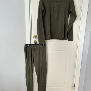Olivgröna ribbade pyjamas  - Säljer ett par olivgröna ribbade pyjamas i ekologisk bomull. Pyjamasen har en slim passform med resår i midjan och är supermjuka och sköna. Perfekta för chill eller hemmadagar.