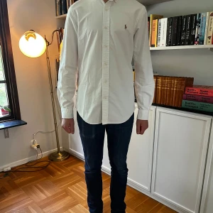 Vit slim fit skjorta  Ralph Lauren Slim  - Riktigt fet raffe skjorta i slim fit, den har i princip inga tecken på användning och nypris är runt 1500kr medan vårt pris ligger på endast 599kr! Modellen är 176 och väger 60kg. Hojta till om ni har frågor eller funderingar! 