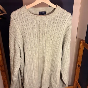 Beige kabelstickad tröja från GANT - Säljer en beige kabelstickad tröja från GANT i storlek L Oversized Look. Tröjan har klassisk rund halsringning, ribbade muddar och ett snyggt stickat mönster. Tillverkad i 100% bomull, perfekt för lager-på-lager under hösten och vintern.