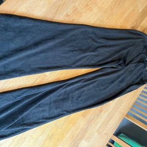 Svarta vida mjukisbyxor Gina Tricot - Svarta mjukisbyxor från Gina Tricot i supermjuk kvalitet. Vida ben och dragsko i midjan för skön passform. Perfekta för chill dagar eller när du vill ha en avslappnad look.