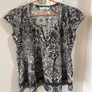 Mönstrad blus från Odd Molly - Säljer en snygg blus från Odd Molly i storlek S med ett detaljerat paisleyinspirerat mönster i svart, grått och ljusrosa. Fint skick!🩶