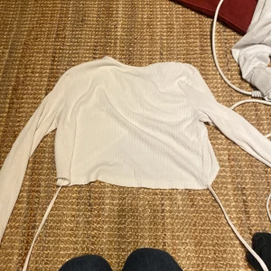 En cream tröja - En tröja som är typ en cream färg och går att knyta där bak, den ganska kort och långärmad. Säljer den då jag inte använder den