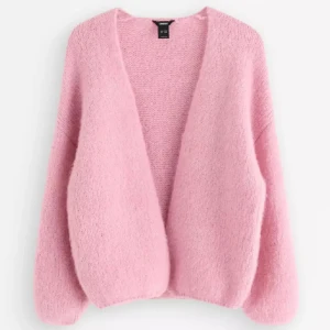 Ljusrosa stickad kofta från Lindex - Supermjuk och fluffig ljusrosa stickad kofta från LinDEX. Koftan har en öppen front utan knappar, långärmade ärmar och en oversized passform som ger en chill vibe. Perfekt att slänga på sig när det är lite kyligt ute.
